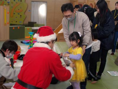 サンタさんからプレゼントをもらうおめかしした女の子